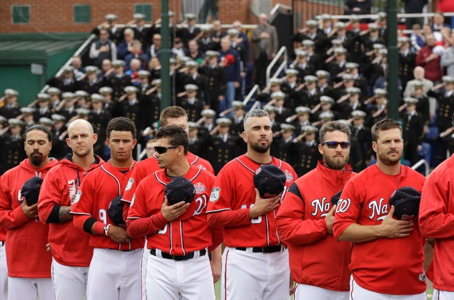 With Midshipmen in the stands behind them, the Red Sox stand for the 'Star-Spangled Banner.'