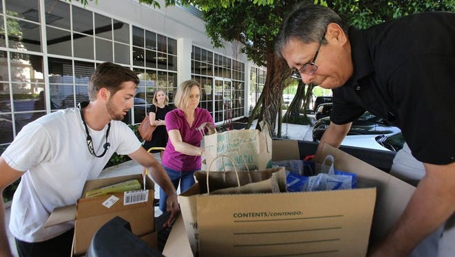 From left, University of Florida student Tyler Fogt, and Karis Engle and Julio Mariaca of the Glades Initiative, pick up food donations at the ‘Daily News’ during the Empty Your Pantry food drive, April 29, 2016. The Glades Initiative received 800 pounds of food, thanks to reader donations. Damon Higgins / Daily News