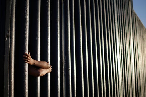 In this 2013 file photo, hands from Daniel Zambrano of Tijuana, Mexico, hold on to the bars that make up the border wall separating the U.S. and Mexico as the border meets the Pacific Ocean in San Diego. One potential bidder on President Donald Trump's border wall with Mexico wanted to know if the government would help if its workers came under "hostile attack." With bids due Tuesday, April 4, on the first design contracts, companies are preparing for the worst if they get the potentially lucrative but controversial job.