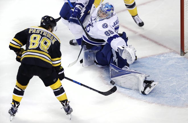 Tampa Bay Lightning goalie Andrei Vasilevskiy, right, makes a save on a shot by Boston Bruins right wing David Pastrnak, left, during the first period in Boston, Tuesday. [THE ASSOCIATED PRESS / CHARLES KRUPA]