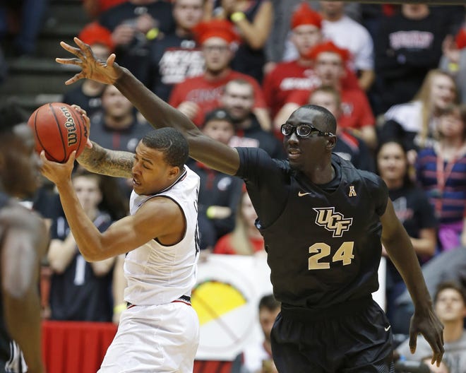 Central Florida sophomore Tacko Fall, right, defends against Cincinnati guard Troy Caupain during the first half of an NCAA college basketball game Feb. 8 in Cincinnati. Fall has announced he will explore his propects in the NBA draft. [AP Photo / Gary Landers]