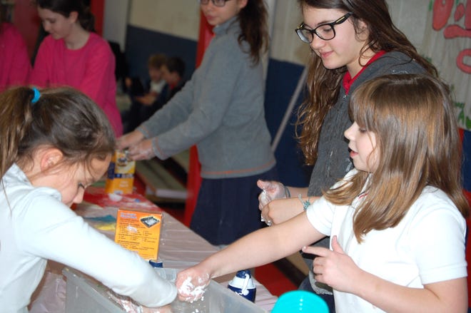Leyla Bible shows Zoe Plemmons (left) and Olivia Kuenzer how to make snow using baking soda and shaving cream during the Hillsdale Preparatory Science Fair. [NANCY HASTINGS PHOTO]