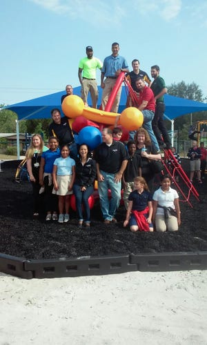 Niagara employees, Groveland Elementary School students and fourth grade teacher Kayla Coxe, far left, pose for a photo at the new Groveland playground. The total donation from Niagara was $106,504 for outfitting two playgrounds, which included rubber mulch and shade structures not in the proposal. “They came in and spoke to us and we gave them the original quote,” Coxe said. “Their exact quote was to 'dream bigger' and give them a new proposal after we got everything we wanted - and they approved it. I was shocked.” [LINDA FLOREA / CORRESPONDENT]