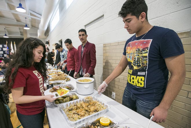 Sydney Guerra, 15, is served rice by Nassir Nassir, 17, during a cultural meet-and-greet Saturday, April 8, 2017, at the Rockford Police Department District 2 station on Broadway. The event was hosted by the department and the local group African Arab Asian American Voice. "I'm most looking forward to eating the colorful rice," Guerra said as she sat down to enjoy her meal. [ARTURO FERNANDEZ/RRSTAR.COM STAFF]