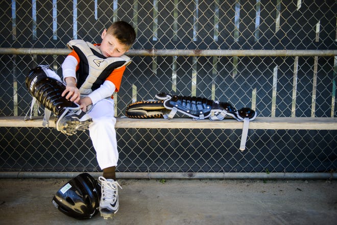 Hope Mills Padres catcher Jayden Elkins puts on his catching equipment during their game against the Hope Mills Braves during Dixie Youth Baseball Opening Day on Saturday April 8, 2017. [Staff photo by Shane Dunlap]