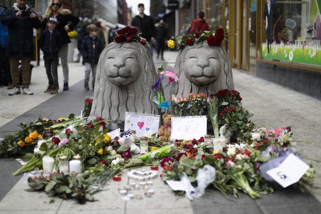 Flowers and candles are placed around stone lions near the department store Ahlens following a suspected terror attack in central Stockholm, Sweden on Saturday. Swedish prosecutor Hans Ihrman said a person has been formally identified as a suspect "of terrorist offences by murder" after a hijacked truck was driven into a crowd of pedestrians and crashed into a department store on Friday. [MARKUS SCHREIBER / ASSOCIATED PRESS]