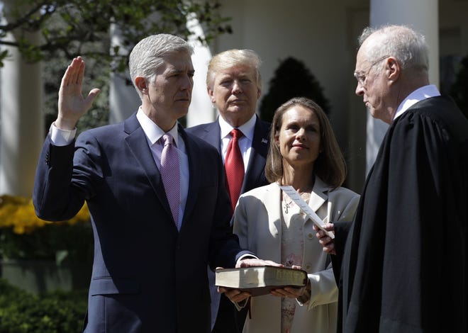 President Donald Trump watches as Supreme Court Justice Anthony Kennedy administers the judicial oath to Judge Neil Gorsuch during a re-enactment in the Rose Garden of the White House White House in Washington, Monday, April 10, 2017. Holding the bible is Gorsuch's wife Marie Louise Gorsuch. (AP Photo/Evan Vucci)