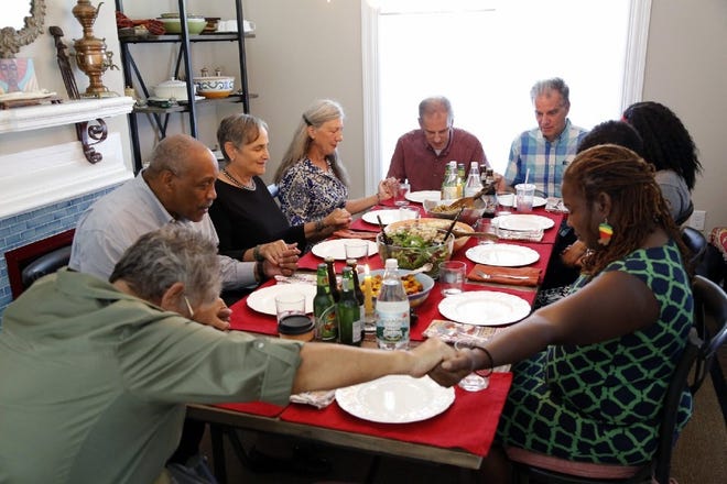 Participants engage in a prayer before a Big Table event at a Columbus home in August. More than 5,000 people attended a Big Table event during its initial occurrence, and The Columbus Foundation is sponsoring a second occurrence in May. [Kyle Robertson/Dispatch file photo]