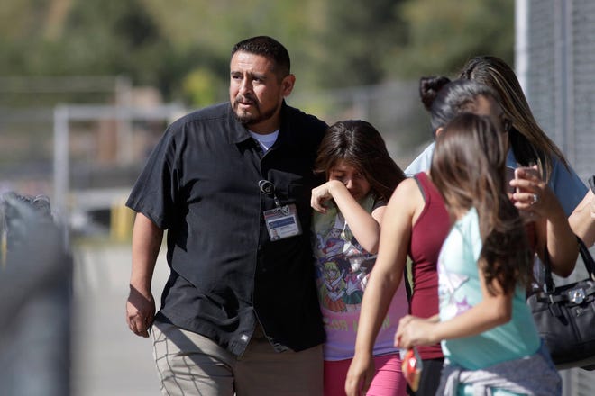 Camilo Rocha, left, comforts his daughter, Serina, a 11-year-old student at North Park Elementary School, after they were reunited at Cajon High School, Monday, April 10, 2017, in San Bernardino, Calif., after a deadly shooting occurred at the elementary school. (AP Photo/Jae C. Hong)