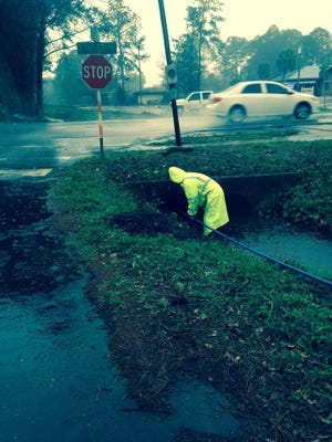 A Public Works employee with the city of Lynn Haven tries to unclog a culvert during heavy rainfall and flooding Jan. 22. [MARGO ANDERSON/CONTRIBUTED PHOTO]