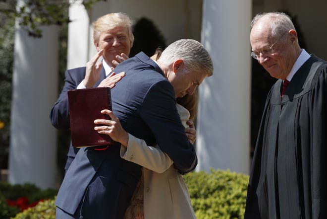 President Donald Trump applauds as Supreme Court Justice Neil Gorsuch hugs his wife, Marie Louise Gorsuch, after a swearing in re-enactment ceremony with Supreme Court Justice Anthony Kennedy, right, in the Rose Garden of the White House in Washington, Monday, April 10, 2017. THE ASSOCIATED PRESS