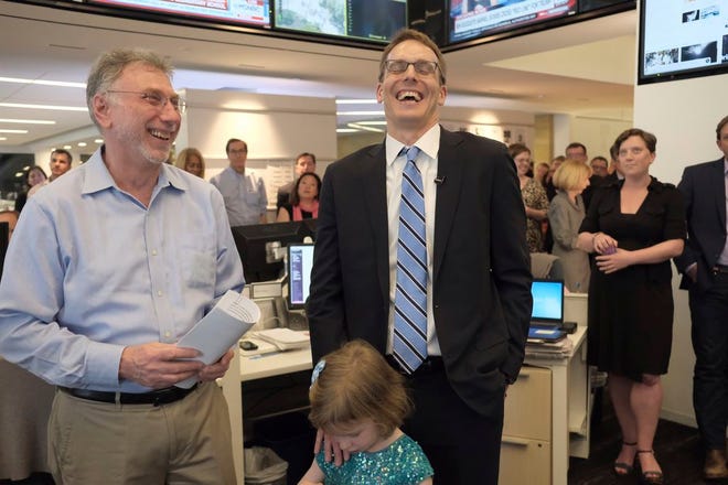 Washington Post editor Martin Baron, left, joins the paper's staff in congratulating David Fahrenthold, center, upon learning that he won the Pulitzer Prize for National Reporting, for dogged reporting of Donald Trump's philanthropy, in the newsroom of the Washington Post in Washington on Monday. (Bonnie Jo Mount/The Washington Post via AP)