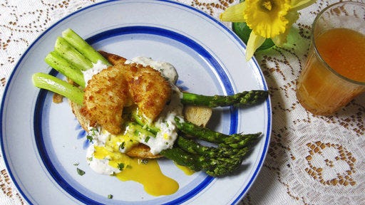 This April 2017 photo shows roasted asparagus toast with a fried poached egg in New York. The base is artisanal toast brushed with olive oil and topped with roasted asparagus. The asparagus can be prepped and pre-roasted and then warmed in the oven before serving. (Sara Moulton via AP)
