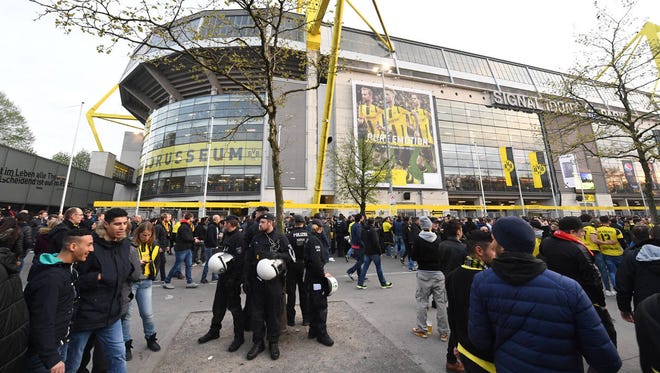 Police officers and fans stand in front of the Signal Iduna Park on Tuesday in Dortmund, Germany. The first leg of the Champions League quarterfinal soccer match between Borussia Dortmund and AS Monaco had been canceled to an explosion. (Associated Press)