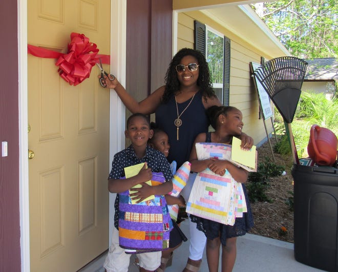 Alex Albury cuts the ribbon with her children, Cyrus, Ariya and Amariana Brown, signifying the start of their new life as homeowners as part of the Flagler Habitat for Humanity program. [News-Tribune photos/Danielle Anderson]