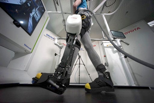A model demonstrates the Welwalk WW-1000, a wearable robotic leg brace designed to help partially paralyzed people walk at the main system with treadmill and monitor, at Toyota Motor Corp.'s head office in Tokyo, Wednesday.