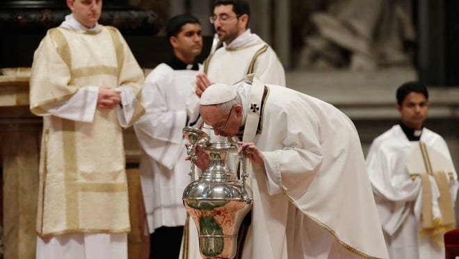 Pope Francis blows inside an amphora containing holy oil during a Chrism Mass in St. Peter’s Basilica at the Vatican Thursday, April 13, 2017. During the Mass the Pontiff blesses a token amount of oil that will be used to administer the sacraments for the year. (AP Photo/Alessandra Tarantino)