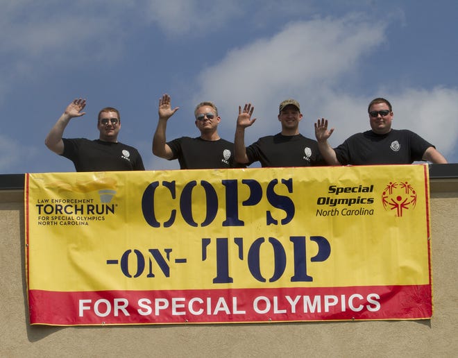 Officers Chapman, Etters, Johnson and Sgt. Welch of the Vanceboro State Prison's PERT Team wave from the roof of Chik-fil-A at the New Bern Mall. Prison employees are raising funds for Special Olympics with the event. [Photo by Bill Hand/Sun Journal Staff]