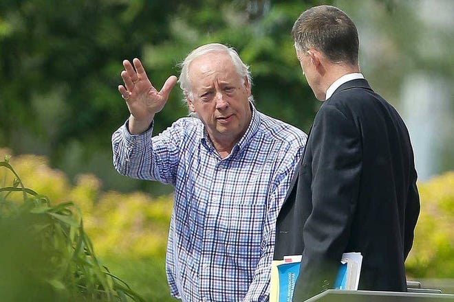 In this file photo, while talking with his attorney, Topeka developer Kent Lindemuth, left, waves to the media on the steps of the federal courthouse. After 59 firearms and ammunition were found in a walk-in vault owned by Lindemuth, a federal judge ruled Thursday that Lindemuth violated terms of his pre-trial release. (File photo/The Capital-Journal)