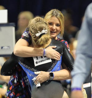 Florida coach Jenny Rowland, hugging gymnast Alex McMurtry after her performance on the floor during the NCAA Gainesville Regional at the Exactech Arena on April 1, is eyeing a top-three finish today. [Brad McClenny/Staff photographer]