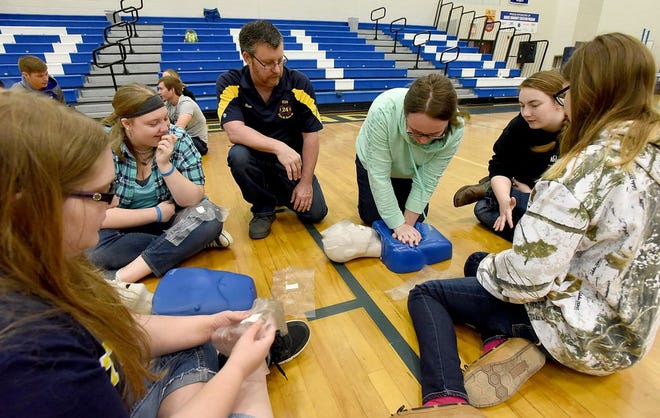 Monroe News photo by TOM HAWLEY Dundee High School senior Sienna Whaley, (center) attempts CPR on the mannequin while Ida firefighter Ron Eby (center left) looks on with other the other high school seniors.