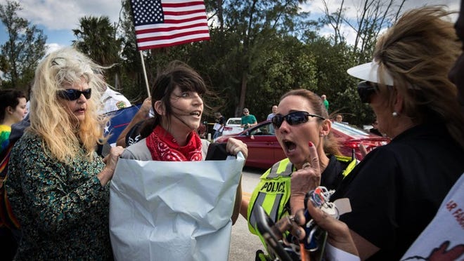 Anti-Trump protestors and President Donald Trump supporters are separated by a Palm Beach police officer as the two sides competed for attention on Bingham Island on March 4, 2017. (Allen Eyestone / Daily News)