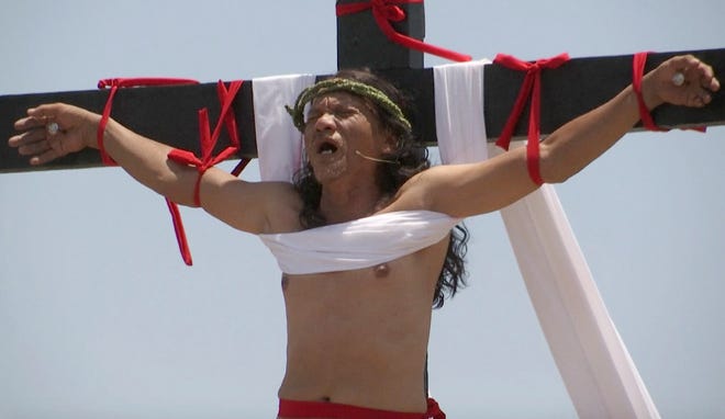 In this image made from video, Filipino penitent Ruben Enaje is nailed to a wooden cross at a crucifixion reenactment during Good Friday rituals on Friday, April 14, 2016 at Cutud, Pampanga province, northern Philippines. Several Filipino devotees had themselves nailed to crosses Friday to remember Jesus Christ's suffering and death.