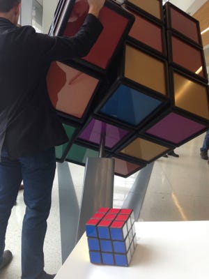 — AP photo by MIKE HOUSEHOLDER 

A traditional Rubik’s Cube sits on a podium in the foreground while a person operates an oversized version shortly after its unveiling Thursday inside the University of Michigan’s G.G. Brown engineering building in Ann Arbor, Mich. Some of the past and present mechanical engineering students designed and built the 1,500-pound tribute.

 to one of the world’s all-time great brain teasers. (AP Photo/Mike Householder)
