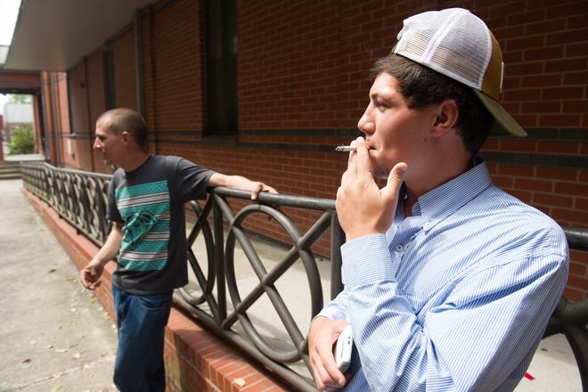 Blake Cauley, right, and Kirk Nyberg smoke outside of the Craven County Courthouse on Thursday afternoon. Craven County commissioners will look at a proposed resolution baning outdoor smoking on the grounds of the main Craven County Courthouse and adjacent Judicial Office Building. [Todd F. Michalek / Sun Journal Staff]
