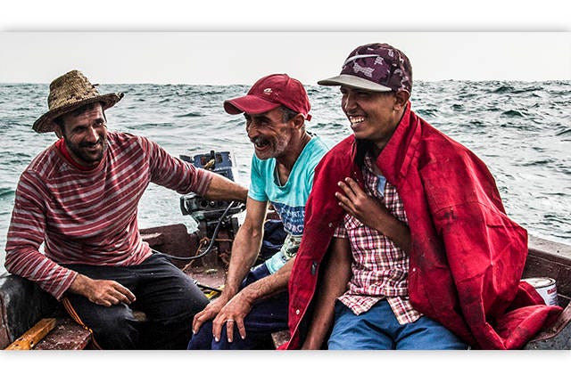 JOVIAL ON THE JOB — A trio of fishermen — Brahim, left, his son, Toufik, right, and Adil — laugh after a day on the sea. (Photo by Tyler Brock)
