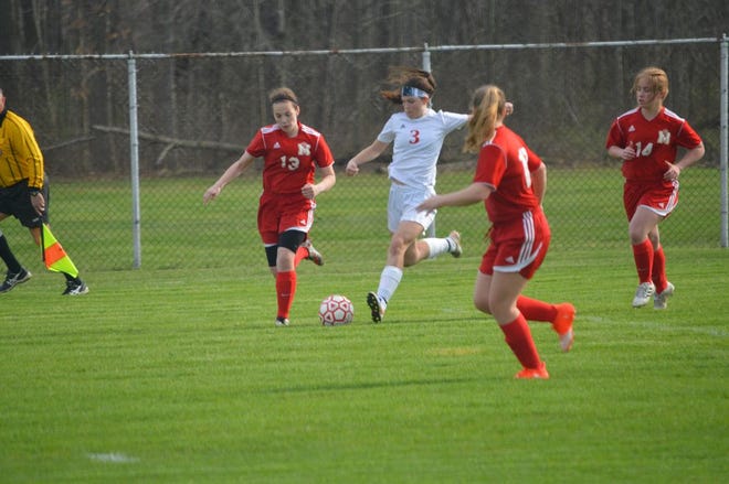 Bedford’s Britney Deiley moves the ball against Monroe defenders Remy Roberts (13), Hannah Connor and Alexis Pickrell (14). (photo courtesy of AMY HELPMAN)