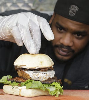 Miguel Navarro inspects a Le Bleu hamburger, made with caramelized onions and blue cheese on top of portobello mushroom and lettuce [AP Photo/Alan Diaz]