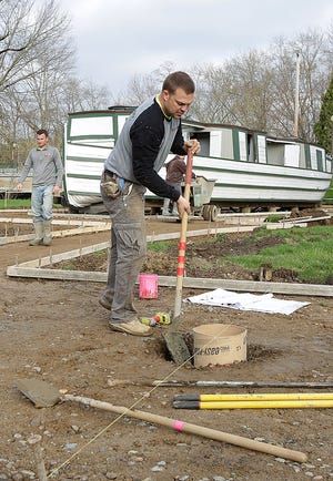 Justin Sloan with Sloan Concrete shovels in cement for the base of an informational kiosk that is being installed along with a walkway around the St. Helena II canal boat in Heritage Park in Canal Fulton.

 (IndeOnline.com / Kevin Whitlock)