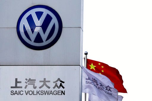 A Chinese national flag flutters near a SAIC Volkswagen, a joint venture between SAIC Motor and Volkswagen's dealer showroom and service center in Beijing. Volkswagen, Europe's biggest automaker, plans to launch its first pure-electric car in China next year.