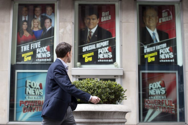 A pedestrian walks past the News Corp. headquarters building in New York displaying posters featuring Fox News Channel personalities including Bill O'Reilly, right, on Wednesday, April 19, 2017. O'Reilly has lost his job at Fox News Channel following reports that five women had been paid millions of dollars to keep quiet about harassment allegations. 21st Century Fox issued a statement Wednesday that "after a thorough and careful review of the allegations, the company and Bill O'Reilly have agreed that Bill O'Reilly will not be returning to the Fox News Channel. THE ASSOCIATED PRESS