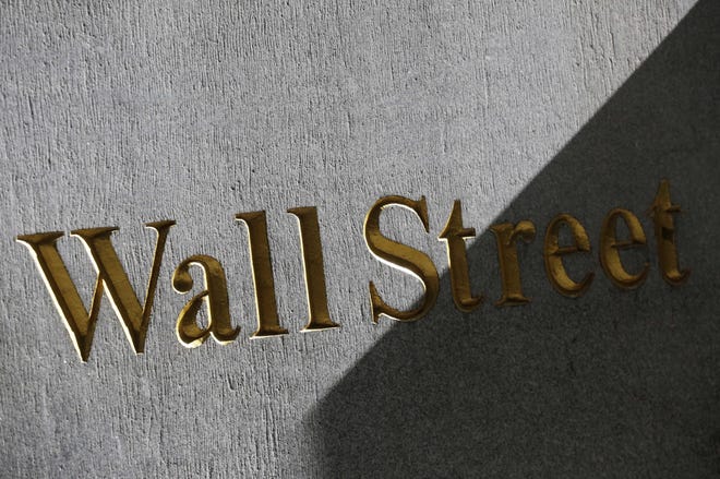 This March 4, 2013, file photo shows a sign for Wall Street on the side of building near the New York Stock Exchange. Stocks are recovering early Thursday, April 20, 2017, as banks rise with bond yields and interest rates. THE ASSOCIATED PRESS