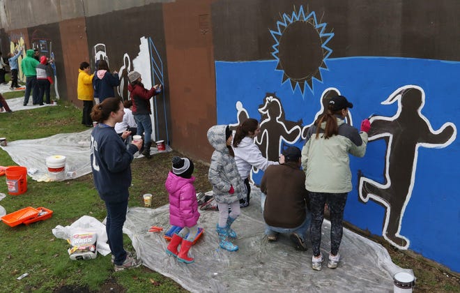 Providence College alumni and families paint scenes on the park walls at Ascham Park as part of Earth Day observances Saturday.