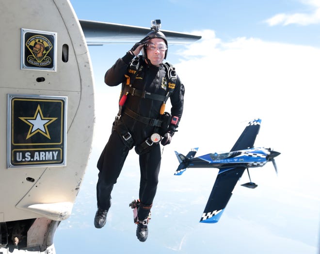 Staff Sgt. Marcus Denniston salutes as he jumps before parachuting to the ground with the U.S. Army Parachute Team, The Golden Knights on Saturday at the Gulf Coast Salute Air Show at Tyndall Air Force Base. [PATTI BLAKE/THE NEWS HERALD]