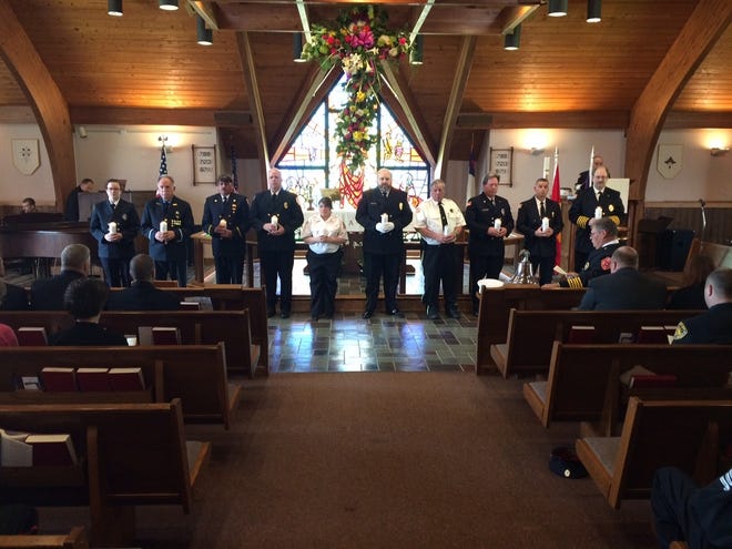 Members of various local volunteer fire companies hold lit candles, honoring fellow members who died last year, during the annual Monroe County Volunteer Firefighters' Association Memorial Service held Sunday, April 23, 2017 at St. Paul Lutheran Church in Tannersville. (Andrew Scott/Pocono Record)