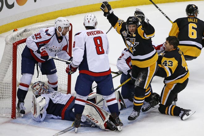 Penguins' Sidney Crosby (87) begins to celebrate a game-winning goal in overtime by Conor Sheary (43) with Washington Capitals goalie Philipp Grubauer (31) still sprawled in goal crease during a game in January.