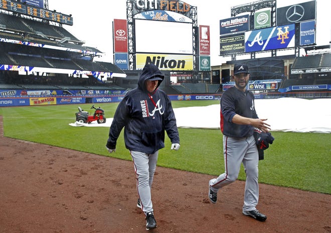 Atlanta Braves relief pitcher Jaime Garcia, right, walks toward the dugout with a Braves coach Tuesday. The game was rained out. [Kathy Willens/The Associated Press]