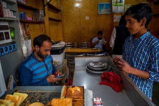 Kashmiri man Umar Rashid, browses internet on his mobile phone as he sits inside his restaurant in Srinagar, Indian controlled Kashmir, Wednesday, April 26, 2017. On Wednesday, authorities ordered internet service providers to block 16 social media sites, including Facebook and Twitter, and popular online chat applications for one month "in the interest of maintenance of public order." The government has often halted internet service in the region in the past in an attempt to prevent anti-India demonstrations from forming. But this is the first time authorities have shut down social media following the circulation of videos of alleged abuse by Indian soldiers. (AP Photo/Dar Yasin)