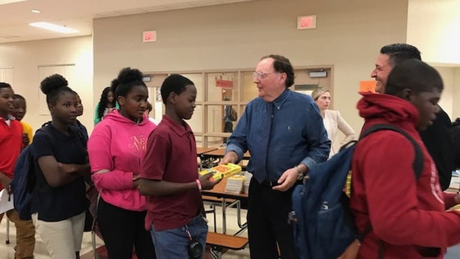 James Patterson hands copies of his books to students at Congress Middle School on April 26, 2017. (Alexandra Seltzer/The Palm Beach Post)