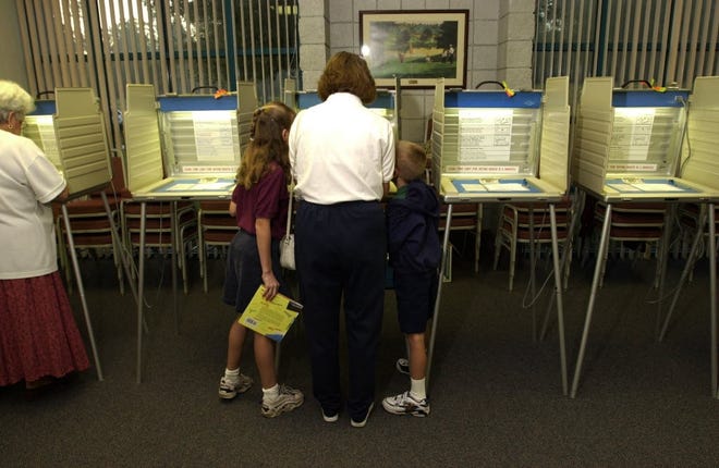 A Florida voter fills out her ballot as her two children watch. [File]