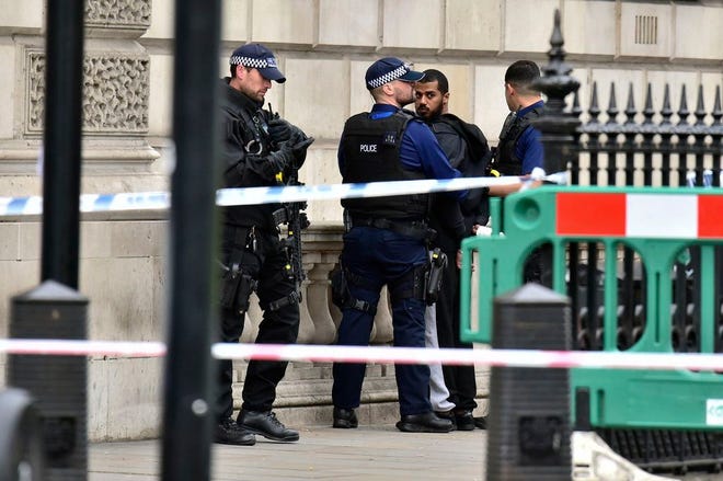 Armed police talk to man at the scene after a person was arrested following an incident in Whitehall in London on Thursday. London police arrested a man for possession of weapons Thursday near Britain's Houses of Parliament.
