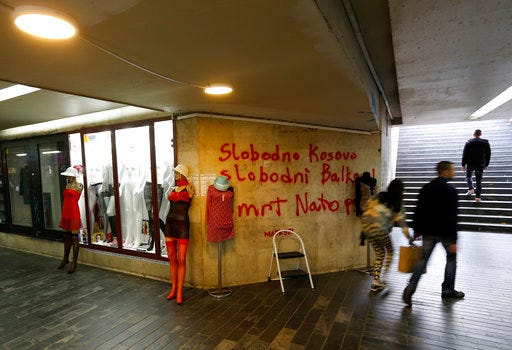 FILE - In this Tuesday April 4, 2017 file photo, people pass through an underground passage with graffiti on the wall that reads: "Free Kosovo, Free Balkan, Death for NATO", in Belgrade, Serbia. The small Adriatic state of Montenegro is set to formally approve becoming a member of NATO, a historic step for the Balkan country that has been split in loyalties to the West and traditional ally Russia. (AP Photo/Darko Vojinovic, File)