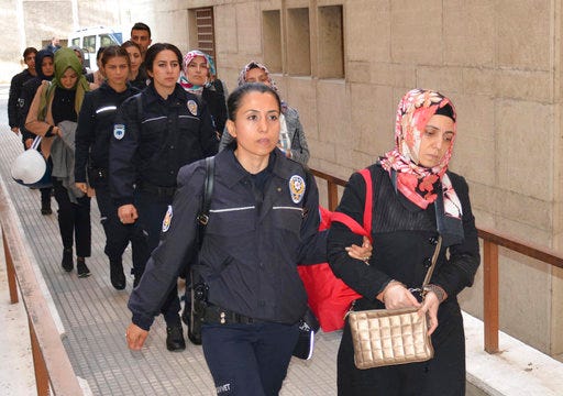 Turkish police officers escort women into a courthouse in Bursa, Turkey, arrested on suspicion of having links with U.S.-based cleric Fethullah Gulen, Thursday, April 27, 2017.  Twenty-five people were detained in Turkey and more than 200 police officers temporarily suspended from their jobs Thursday for suspected links to U.S.-based cleric Fethullah Gulen, following a massive sweep the day before in connection with last summer's failed coup attempt. Gulen has denied the accusations. (Berktug Oncu/DHA-Depo Photos via AP)