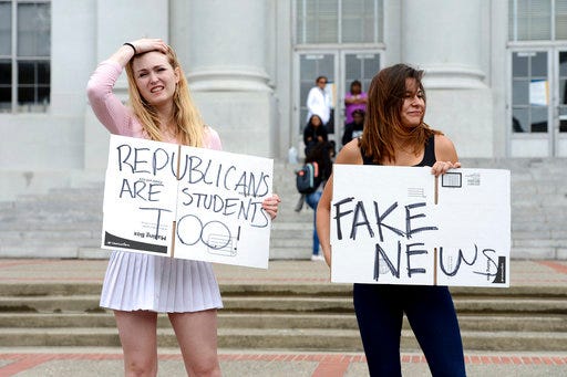 Ashton Whitty, left, 21, and Hailey Carlson, right, 24, University of California, Berkeley students, make their feelings known during a press conference held by the Berkeley College Republicans in Sproul Plaza on the Cal campus in Berkeley, Calif., on Wednesday, April 26, 2017. The event was held to discuss the cancellation of speaker Ann Coulter's appearance on campus. (Dan Honda/East Bay Times via AP)