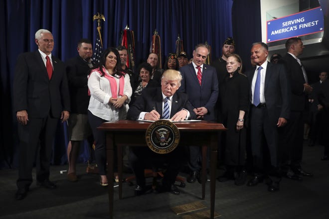 President Donald Trump signs an executive order on “Improving Accountability and Whistleblower Protection” at the Department of Veterans Affairs on Thursday in Washington. [ANDREW HARNIK/THE ASSOCIATED PRESS]