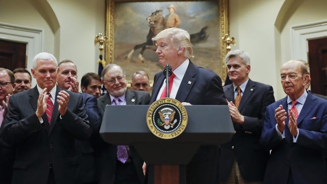 President Donald Trump, center, with Vice President Mike Pence, left, Commerce Secretary Wilbur Ross, right, stands at the podium before signing an Executive Order in the Roosevelt Room of the White House in Washington, Friday, April 28, 2017. (AP Photo/Pablo Martinez Monsivais)